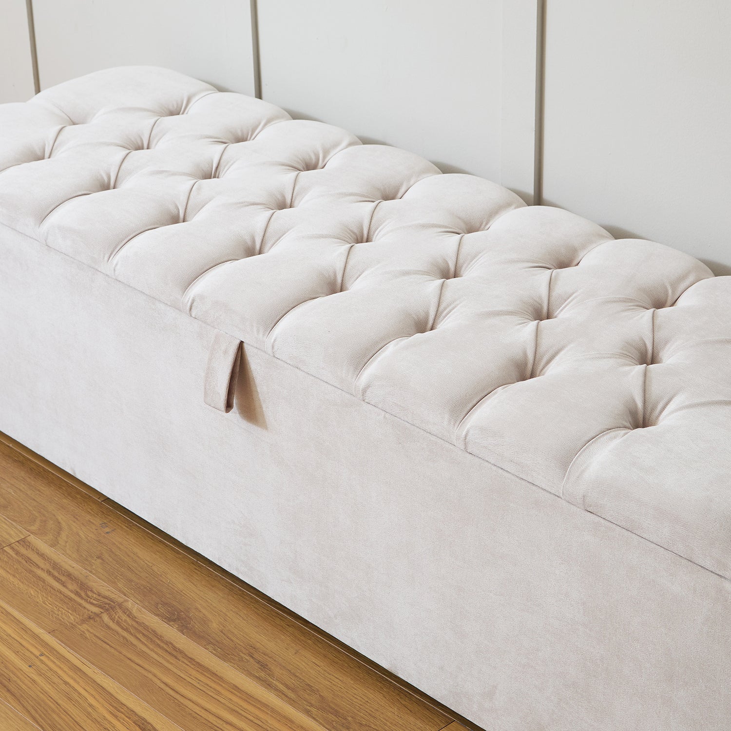 An upholstered ottoman storage box with a beige color, featuring soft buttoned detailing and a cushioned top.