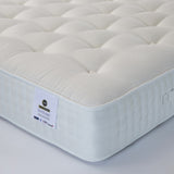 A white, pocket sprung mattress with visible tufting and a label indicating the brand 'Ottoman Bed Store' and the model ' Heritage Natural 2000'.